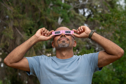 Person wearing Tember Watermelon solar eclipse glasses outdoors